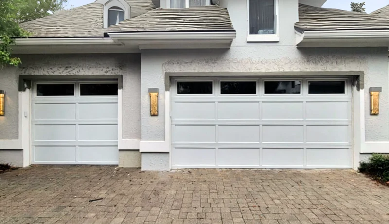 White recessed-panel garage doors with window sections on a stucco home, new garage door installation Ottawa